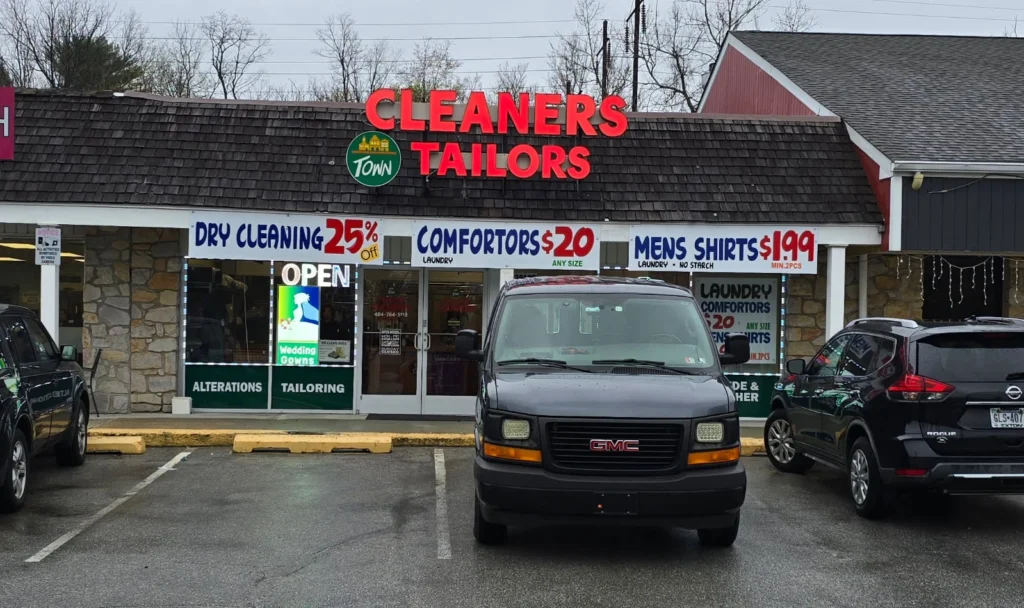 Storefront of Town Cleaners & Tailors in Downingtown, PA, featuring promotional signage for dry cleaning, shirt laundering, and tailoring services.